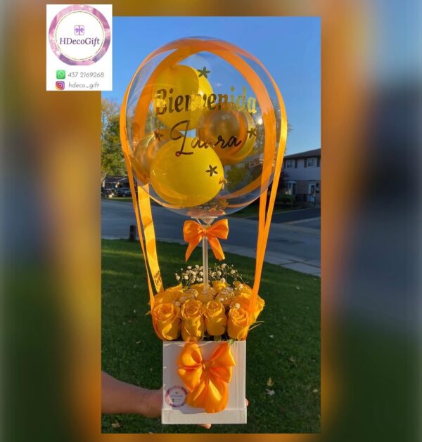 Yellow-themed welcome gift arrangement with roses and a personalized balloon reading 'Bienvenida Laura