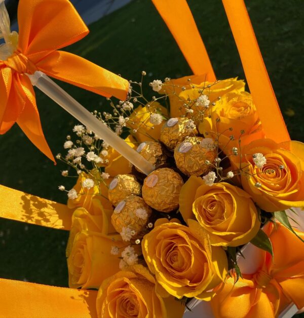 Yellow-themed welcome gift arrangement with roses and a personalized balloon reading 'Bienvenida Laura